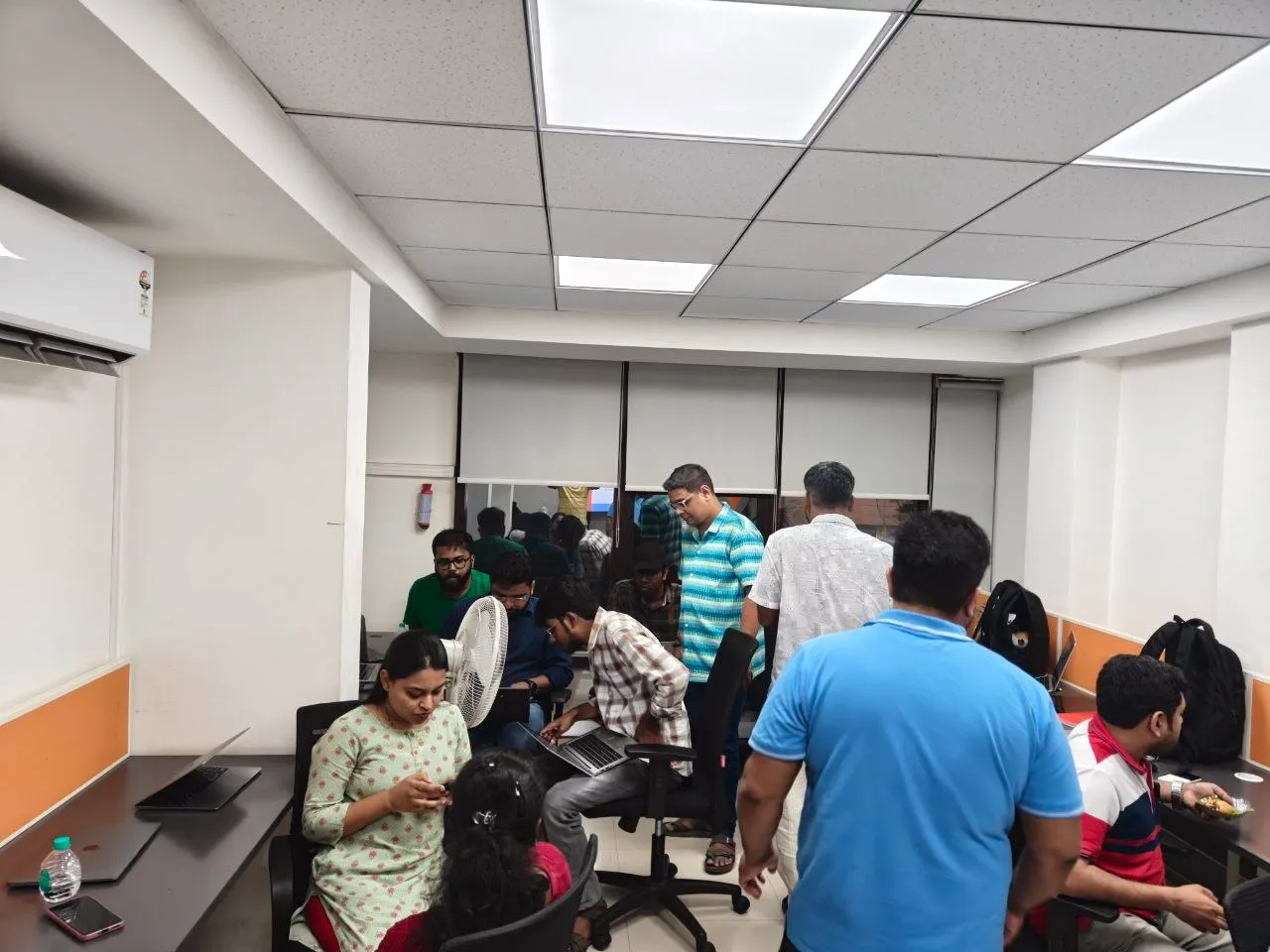 A busy room of meetup attendees working on laptops and talking